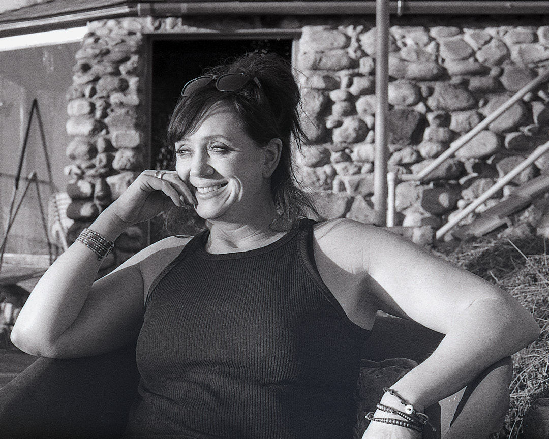 A woman smiling while seated outdoors