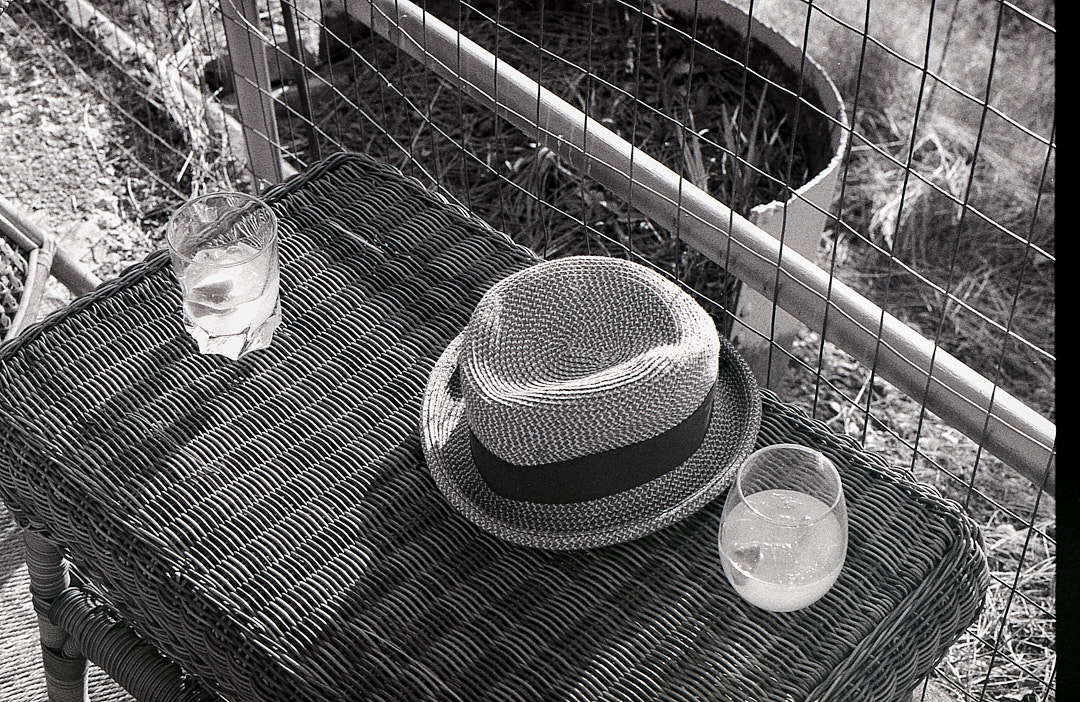 A hat and two glasses on a wicker table