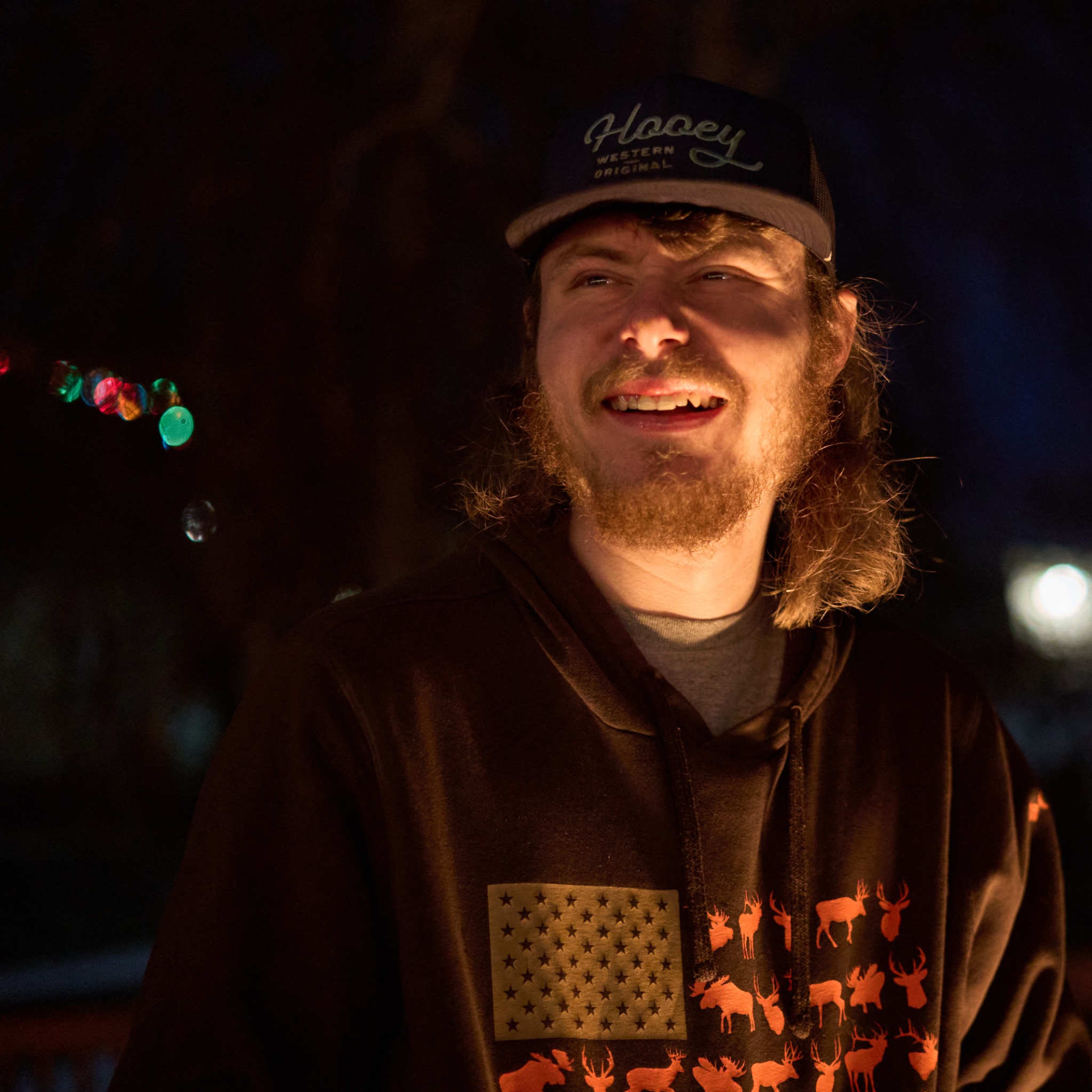A young man lit by a fire outdoors at night